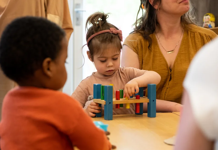 Een moeder speelt met twee peuters met houten blokken