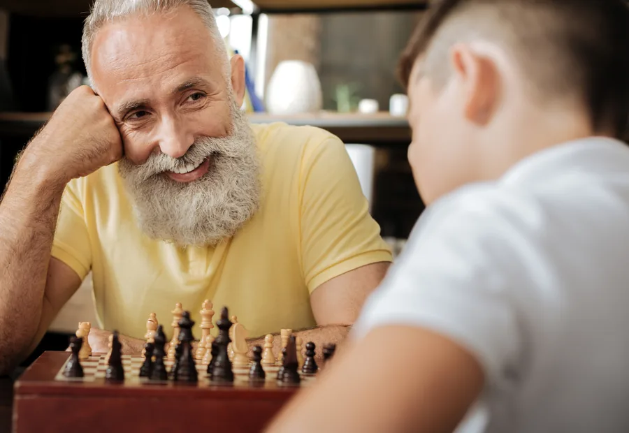 Een oudere man en een jongen spelen samen een spel schaak
