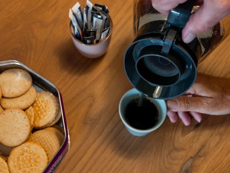 Koffie inschenken bij een koekje tijdens een inloopochtend